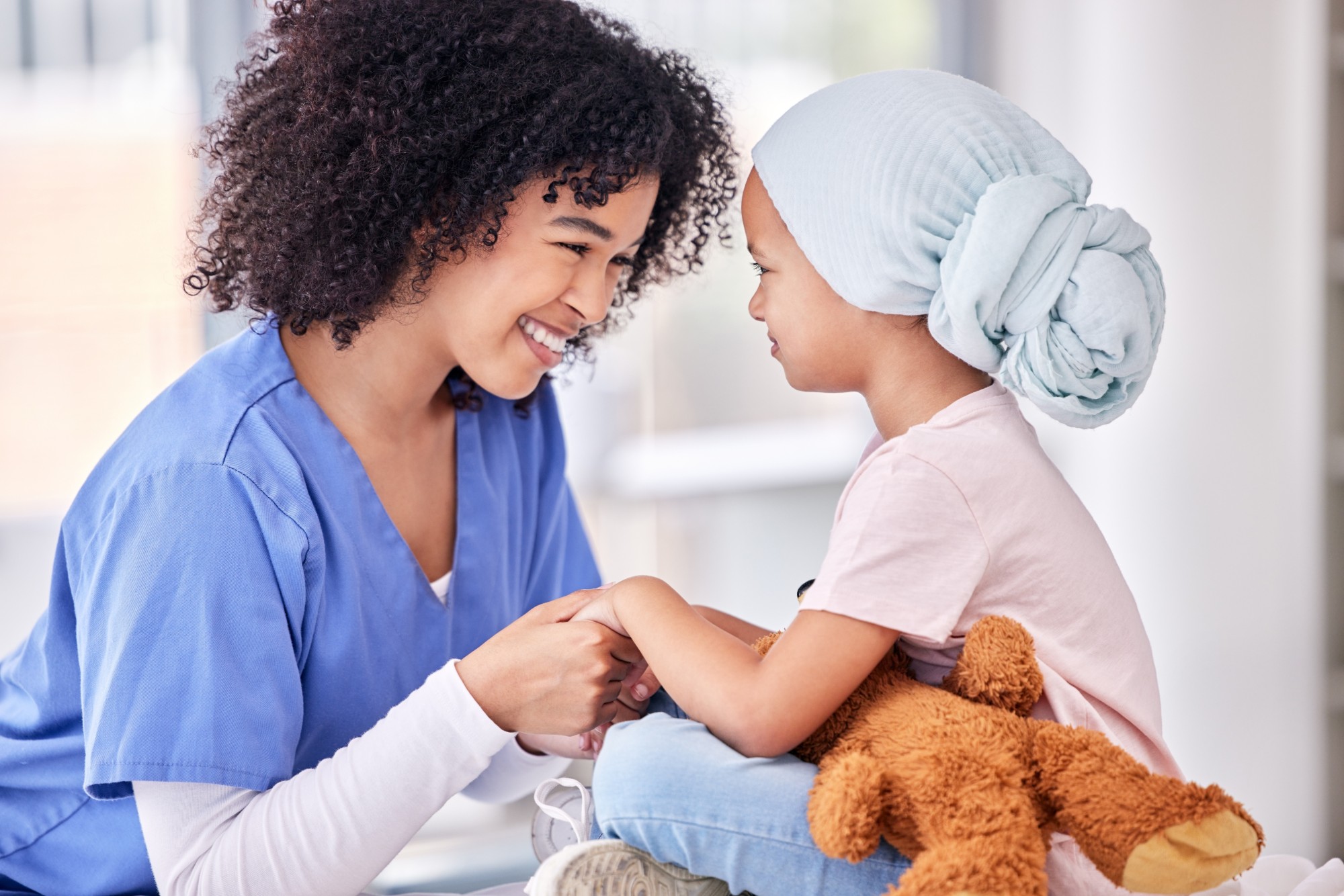 Nurse holding hands with a young patient, sharing a smile