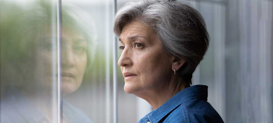 Senior woman looking out window thoughtfully