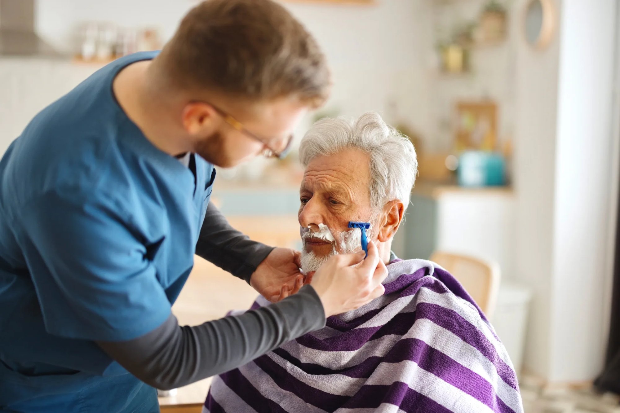 Caregiver helping elderly man shave